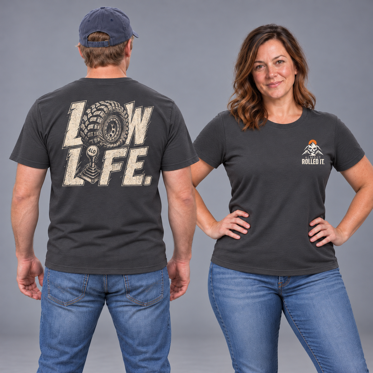 Male back and brunette female front studio views of the Dark Grey Low Life tee, with tire-and-shifter back lettering and small ARI chest mark.