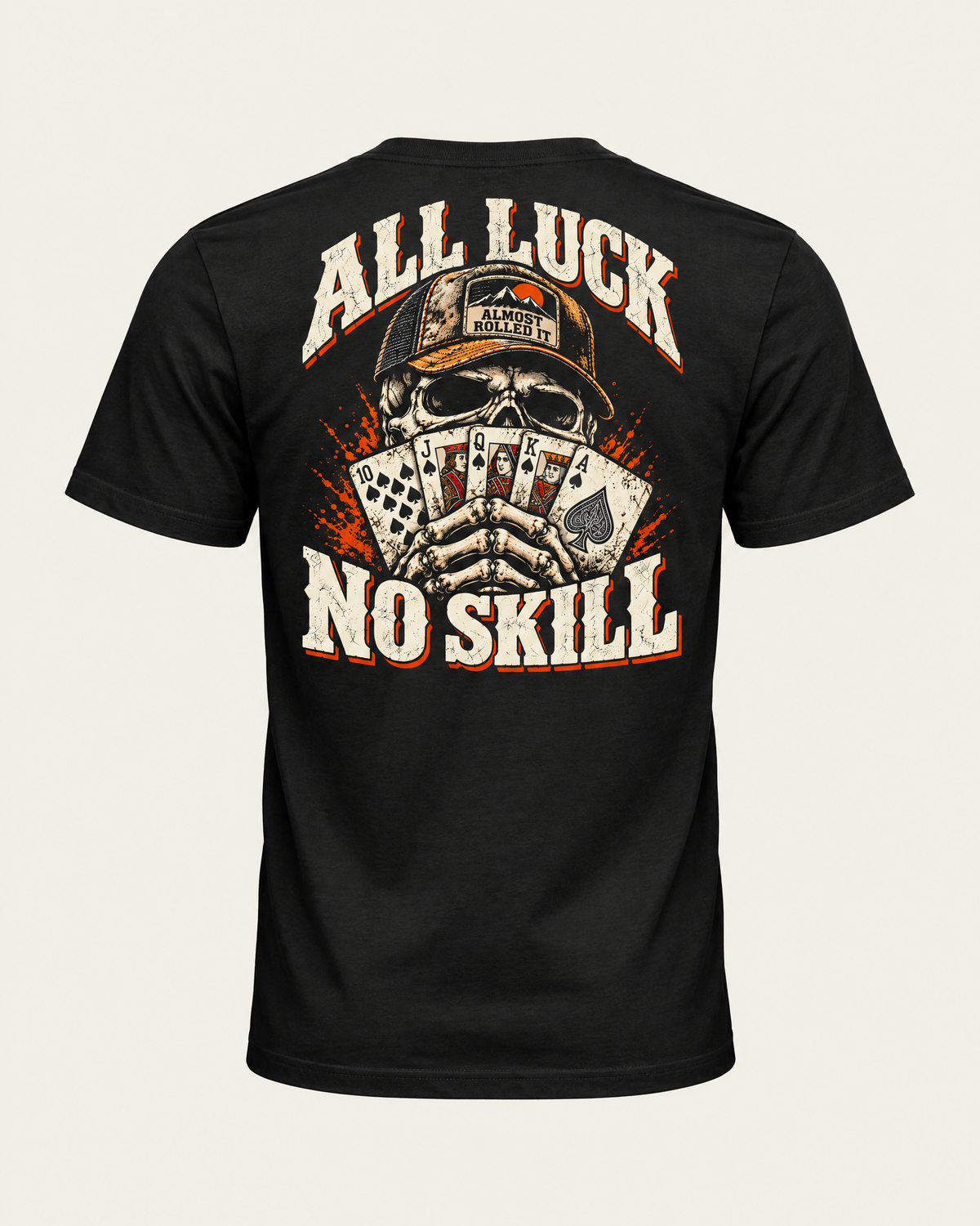 All Luck No Skill tee in vintage black, back view: skull in a trucker cap holding a royal flush of spades, cream and orange lettering