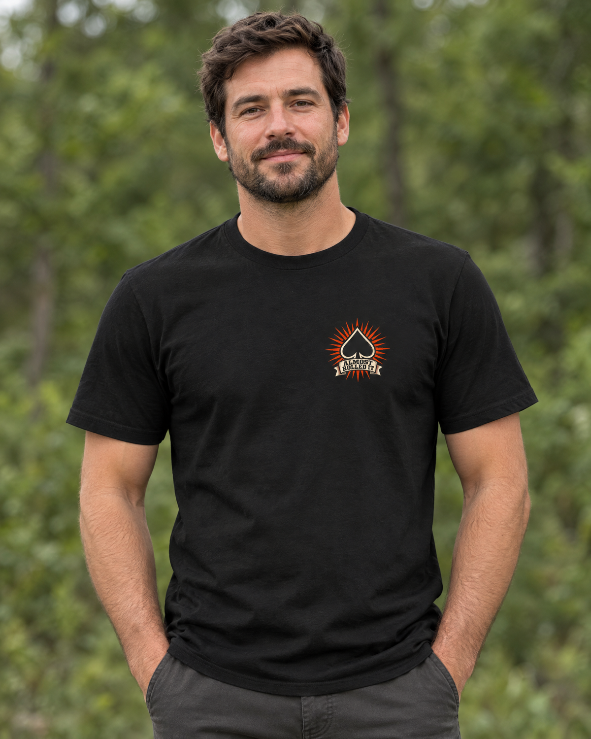 Front of the All Luck No Skill tee on a model: small spade chest logo with an orange burst
