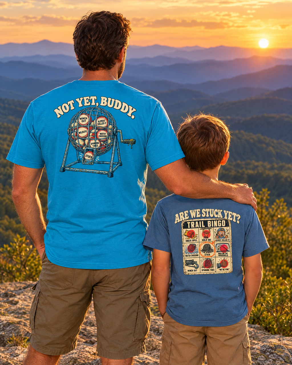 Father and son on a mountain overlook at sunset, seen from behind: Not Yet, Buddy tee and Trail Bingo youth tee