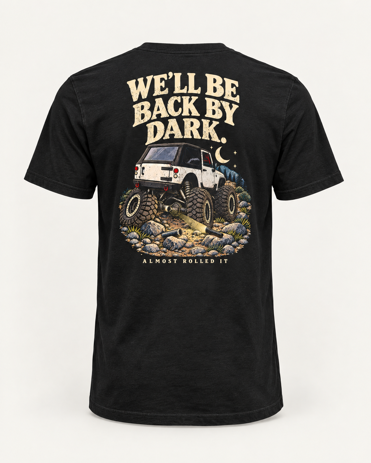 Back By Dark tee in vintage black, back view: cream WE'LL BE BACK BY DARK. lettering over an illustrated white rig crawling moonlit rocks, ALMOST ROLLED IT below