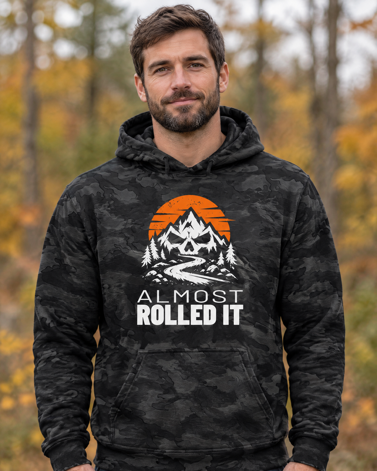 Man wearing the Almost Rolled It Camo Hoodie, front view, in an autumn forest