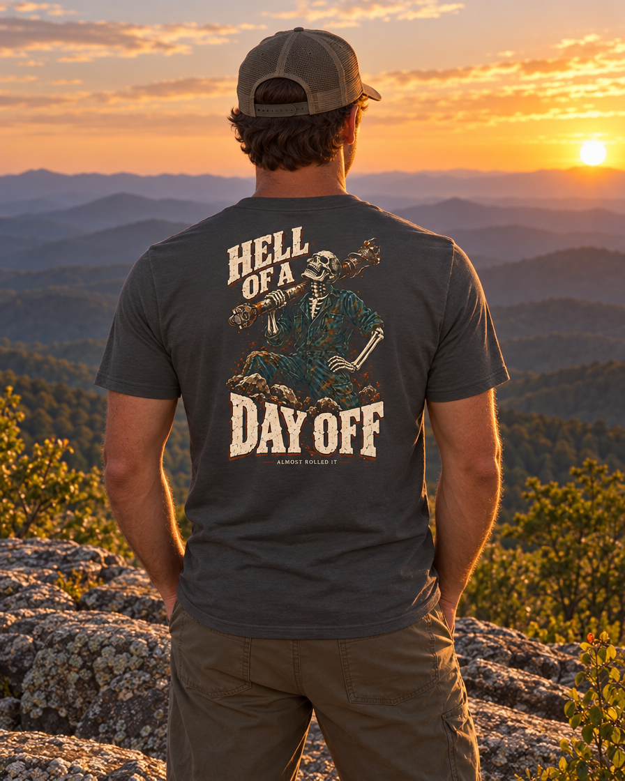 Man on a Blue Ridge ledge at sunset wearing the dark grey Day Off tee, back print visible