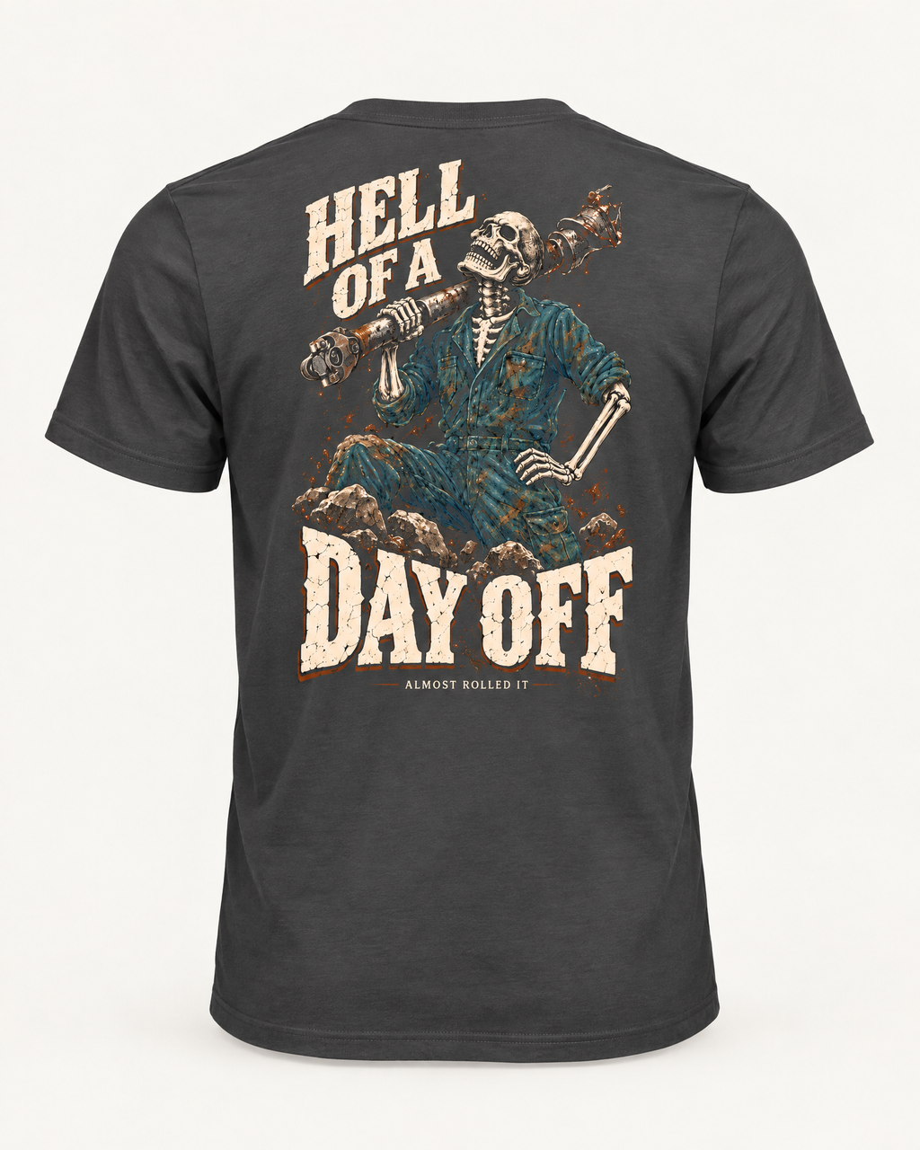 Day Off tee in dark grey, back view: HELL OF A DAY OFF in cream lettering around a skeleton in coveralls with a driveshaft over its shoulder