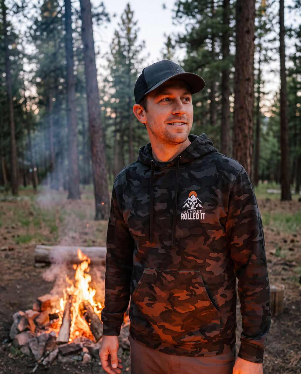 Front of the 4Lo Skull camo hoodie by a campfire: small chest logo