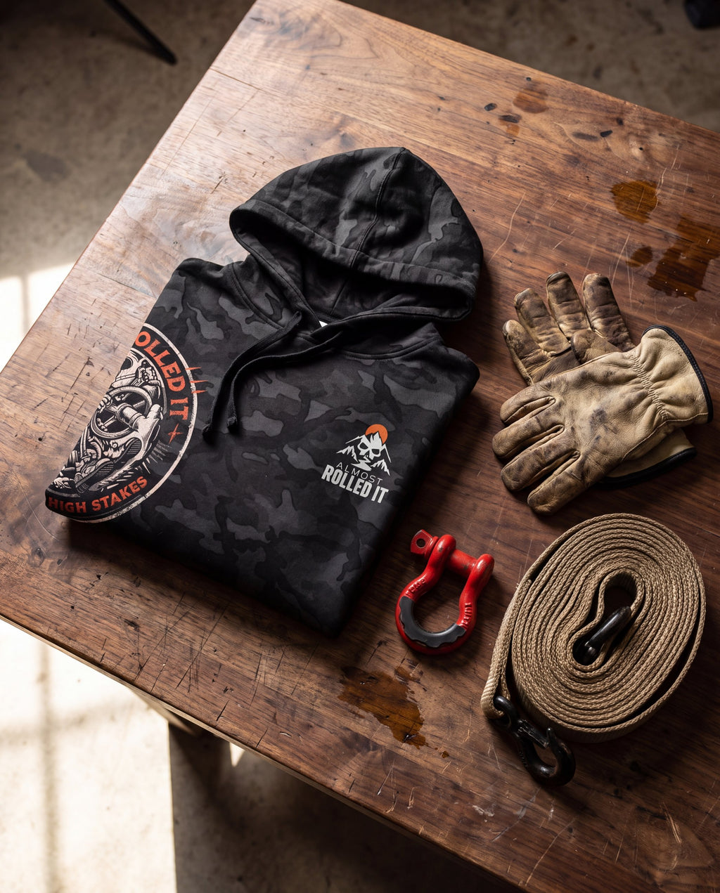 4Lo Skull camo hoodie folded on a walnut workbench with gloves, shackle and strap