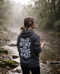 Woman in the asphalt Tons & 42s hoodie at a misty creek, back print showing