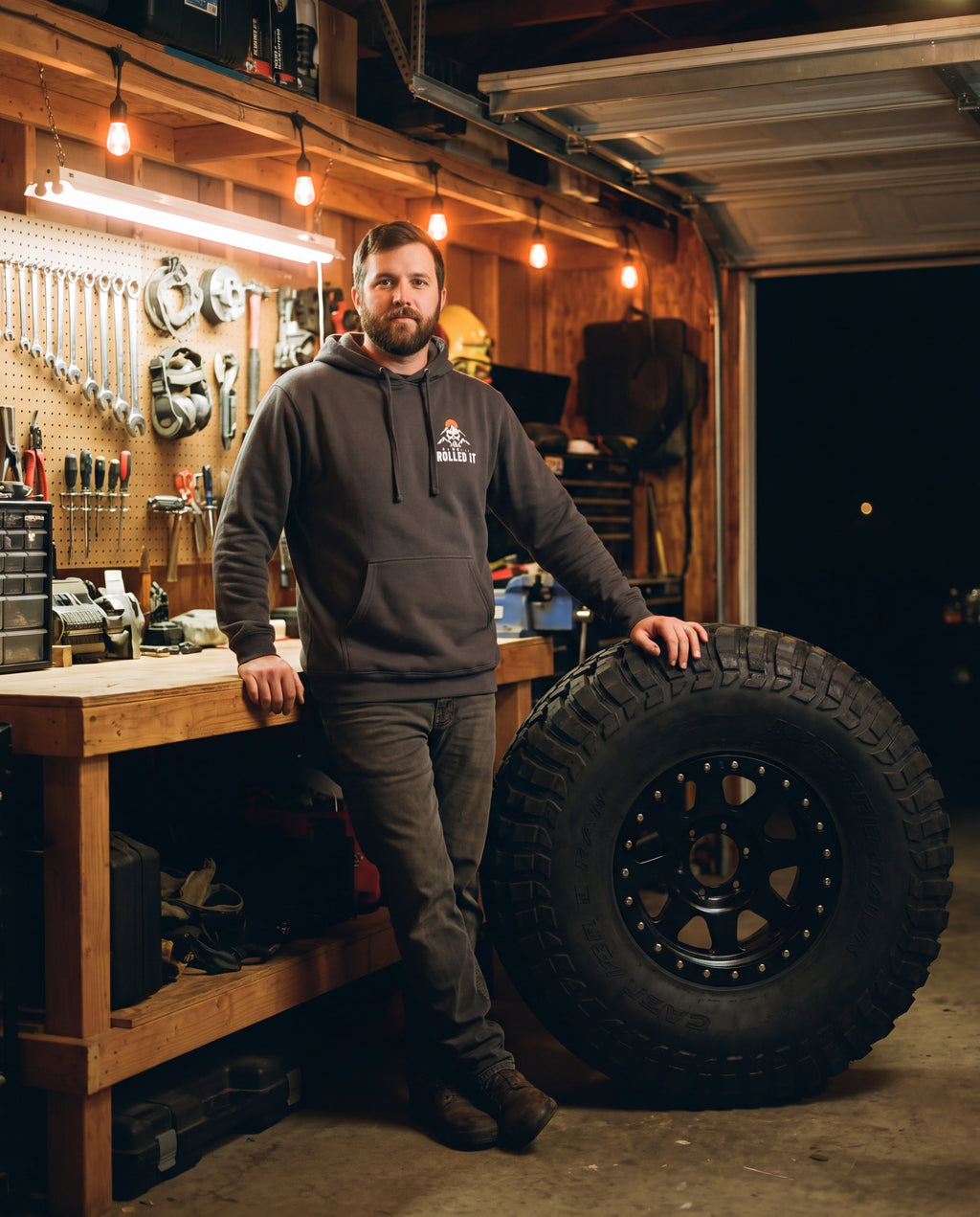 Man in the asphalt Tons & 42s hoodie in a garage next to a 42-inch tire
