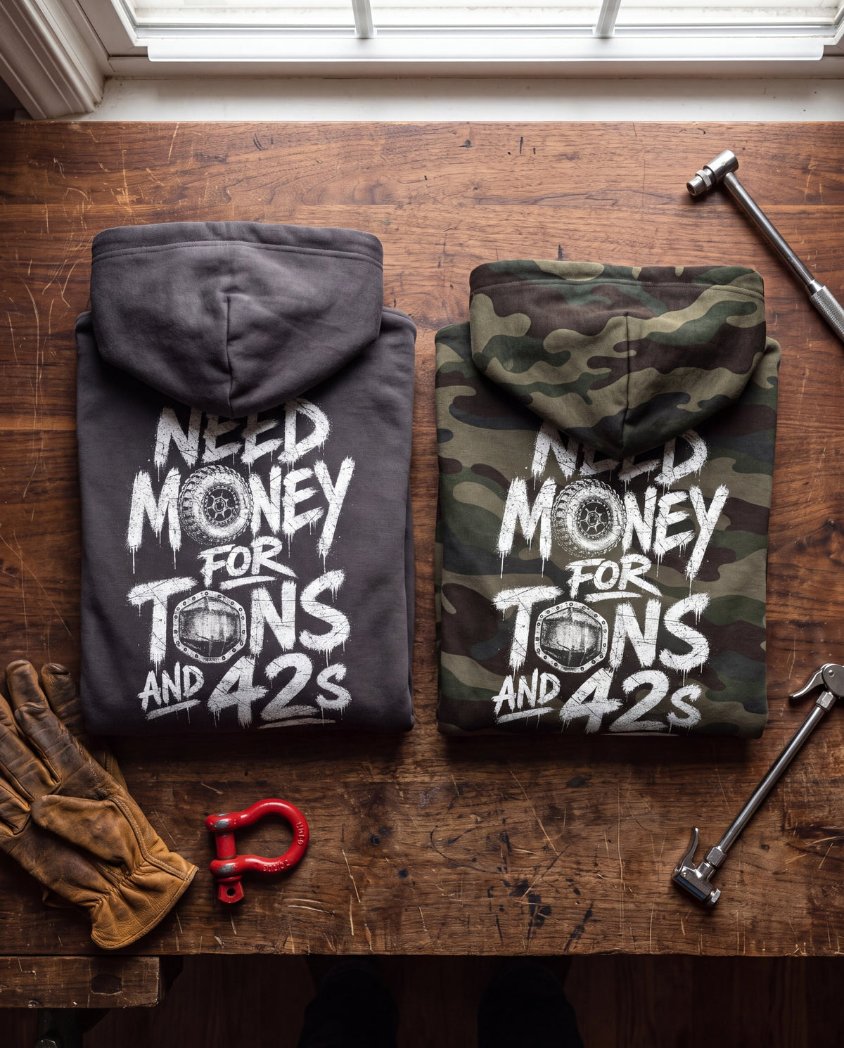 Asphalt and forest camo Tons & 42s hoodies folded on a workbench