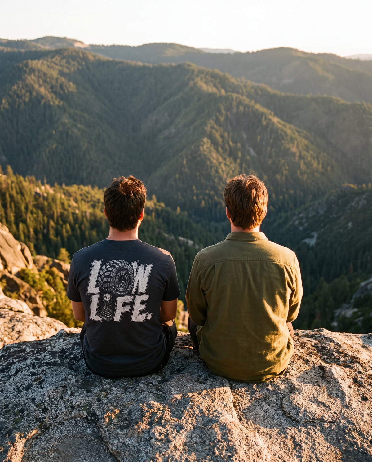 Two friends on a rock ledge at sunset, one in the Low Life tee