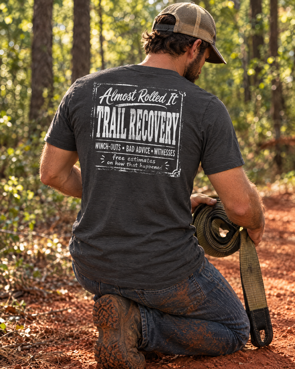 Man coiling a recovery strap on a red-clay trail in the Trail Recovery Badge tee