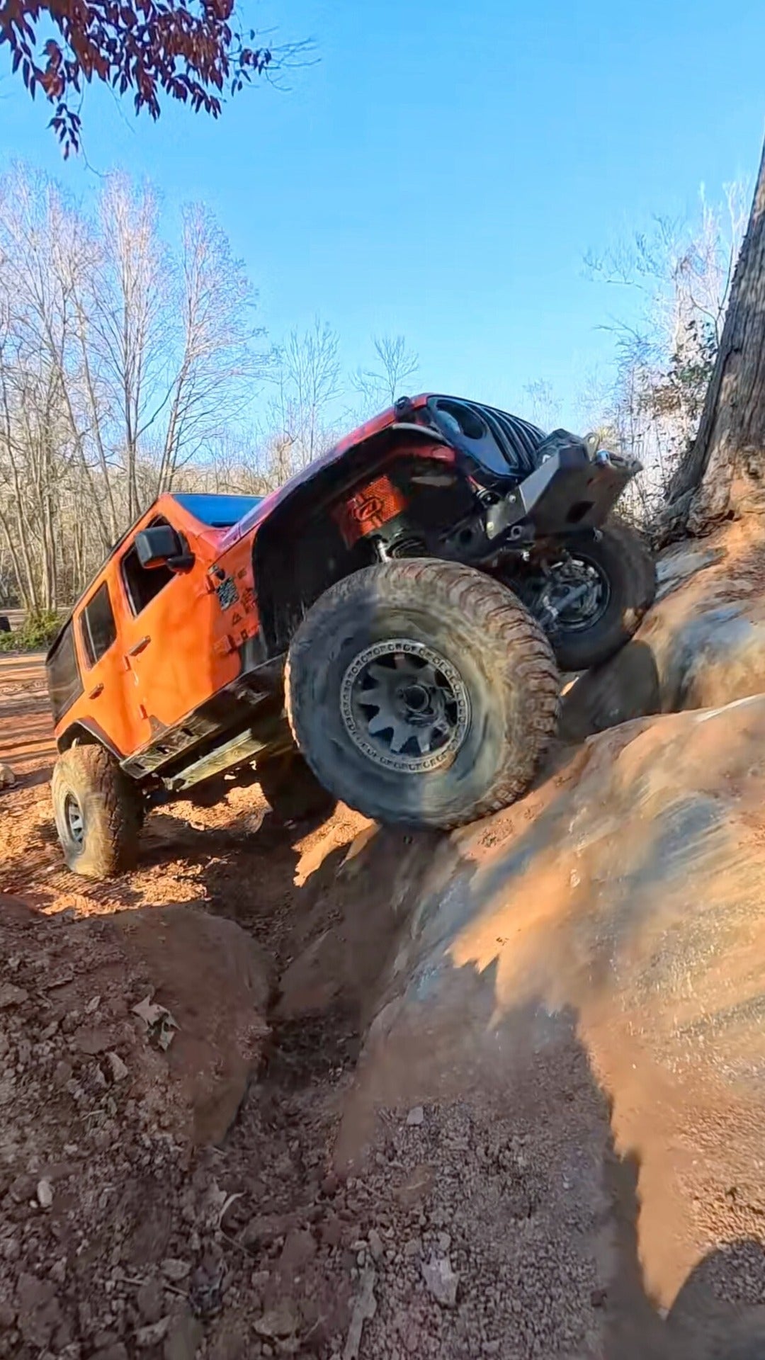 Orange Jeep climbing a steep rock ledge at Between the Threes, Gulches