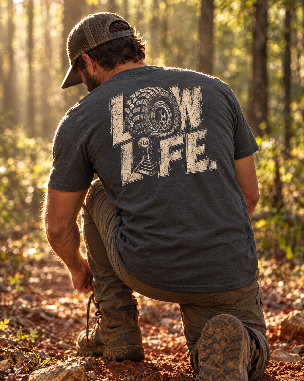 Man kneeling on a red-clay trail in the Low Life tee