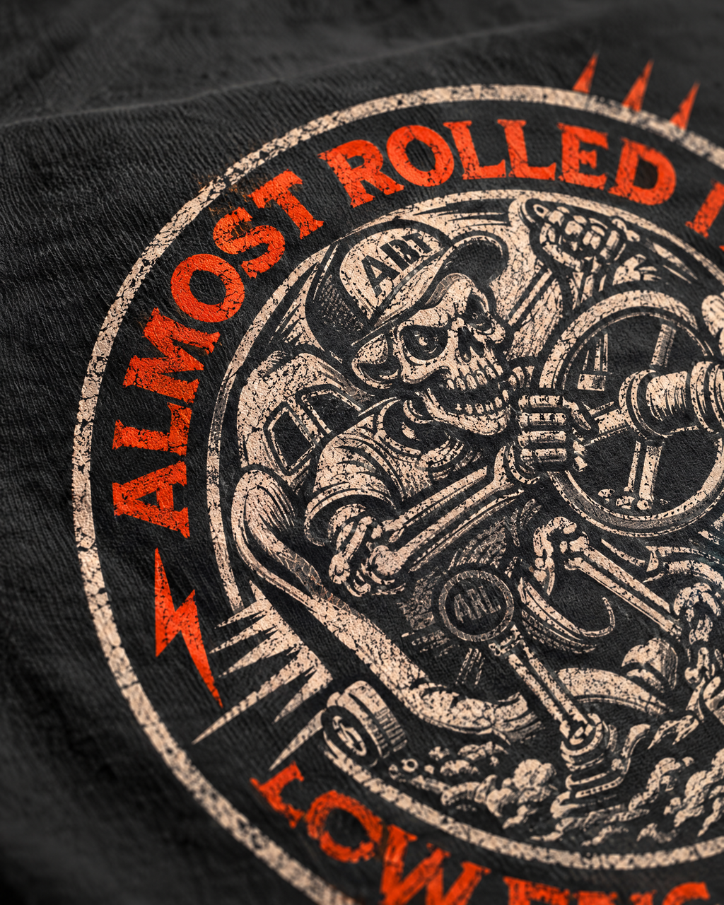 Close-up of the 4Lo Skull badge print: skeleton driver and orange lettering on cotton
