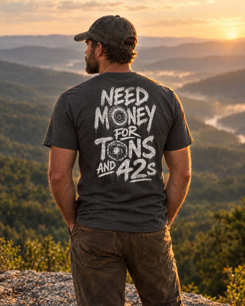 Man wearing the dark grey Tons & 42s tee on a mountain ledge at sunset, back print showing