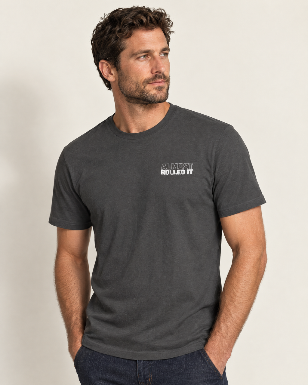 Front of the dark grey Tons & 42s tee on a model: small white Almost Rolled It wordmark