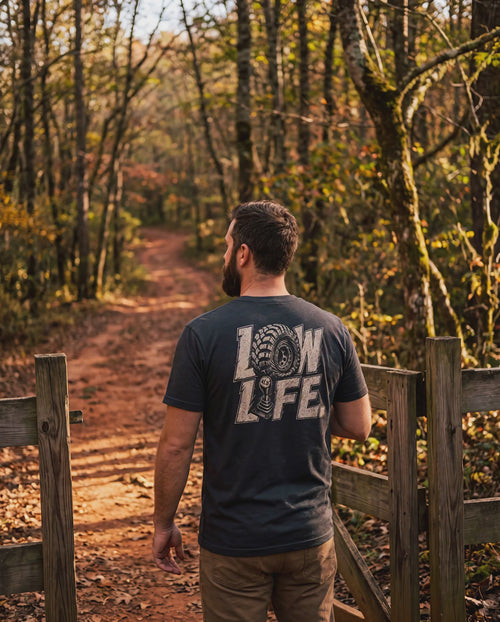 Man in the Low Life tee at an autumn trailhead gate